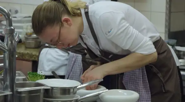 Chef prepara ingredientes en un mortero, escena digna de películas sobre cocina.