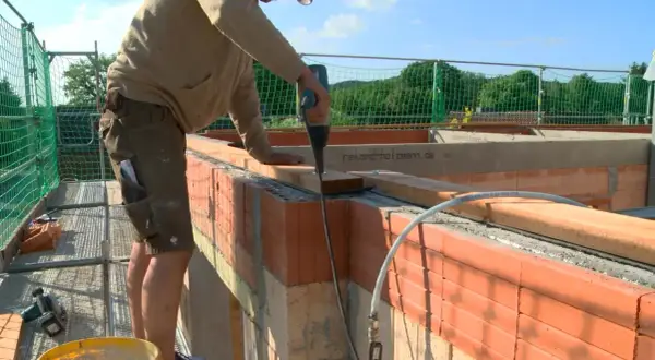 Handwerker arbeitet am dachstuhl aufbau. Mit Akkuschrauber werden Holzbalken befestigt.