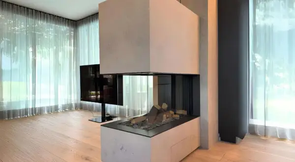 Moderner Kamin Neubau mit Glasfront und Holzelementen, umgeben von hellen Vorhängen und Holzboden.