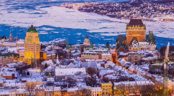 Quebec Winter: Eisbedeckter Sankt-Lorenz-Strom und schneebedeckte Dächer der Altstadt, beleuchtet vom Abendlicht.
