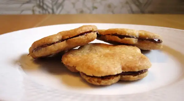 Tre chokladfyllda tuile-kakor på en vit tallrik. Ett enkelt tuile recept som ger läckra småkakor.