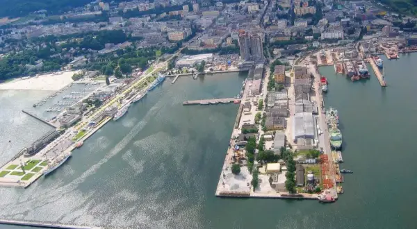 Rozległy port morski z licznymi statkami, jachtami i budynkami przemysłowymi.