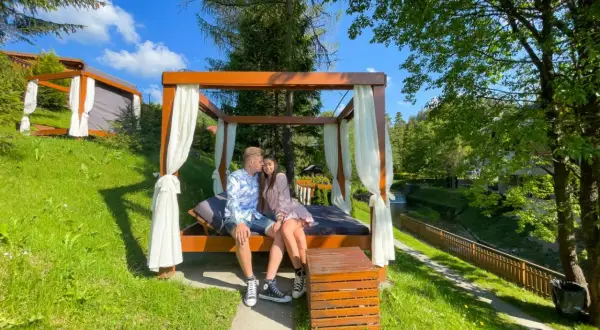 Para spędza romantyczny last minute weekend dla dwojga na łóżku pod baldachimem, otoczona zielenią i strumykiem.