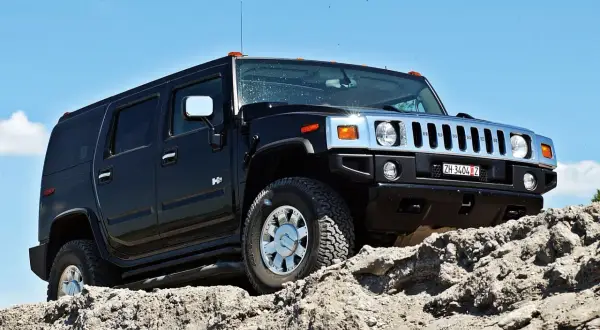 Czarny Hummer H2 pokonuje skalisty teren pod błękitnym niebem.