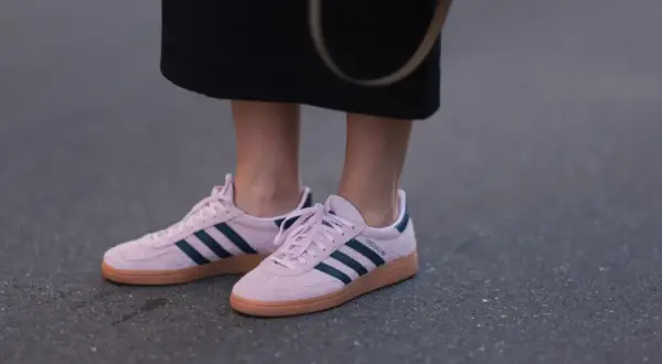 Różowe buty sportowe Adidas z granatowymi paskami i brązową podeszwą.