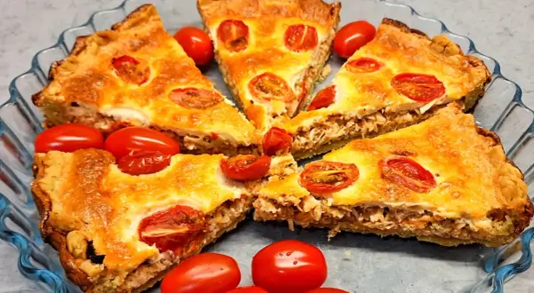 Kawałki pysznej tarta z kurczakiem i pomidorkami koktajlowymi, podane w szklanej formie.
