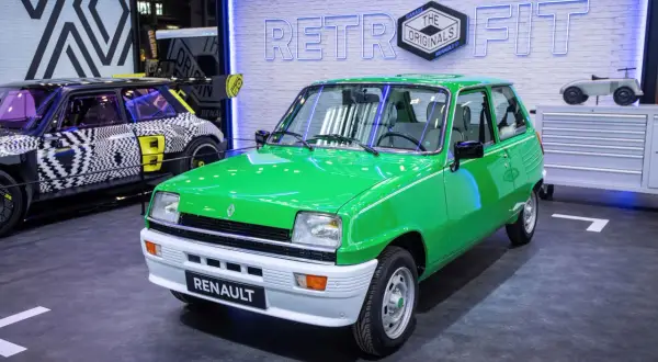Zielony Renault 5 z napisem "RENAULT" na zderzaku. Obok niego futurystyczny model z czarno-białą grafiką. To przykład przerabiania aut na elektryczne.