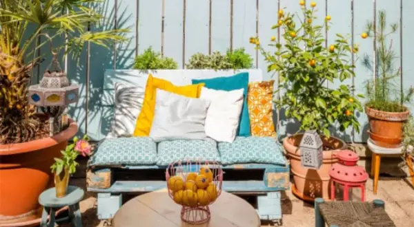 Un rincón perfecto para tus ideas chill out: un sofá de palets con cojines coloridos, plantas y faroles.