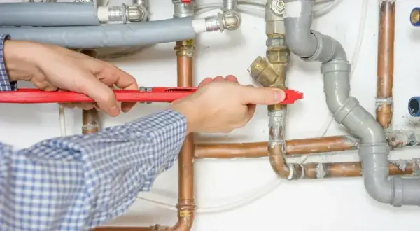 Hydraulik z kluczem nastawnym naprawia instalację wodną.