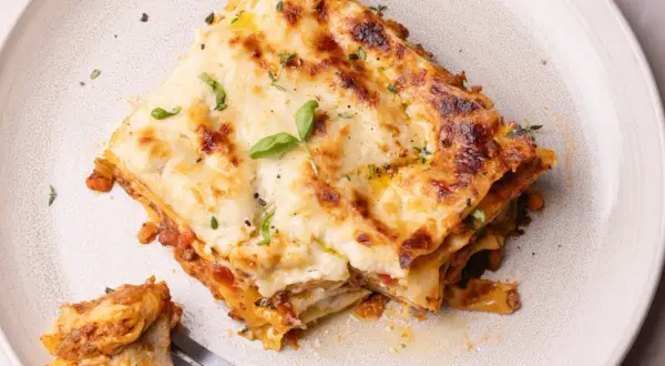 Une part de lasagne généreuse, dorée et gratinée, garnie de basilic frais. Une recette lasagne originale qui met l'eau à la bouche.