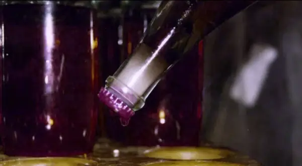 Bottiglia di vino rosso con tappo viola, una goccia cade. Il dégorgement significato è la rimozione del sedimento.