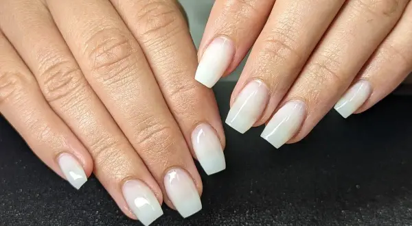Mains aux ongles blancs laiteux, d'une douceur infinie. Une manucure parfaite pour un look épuré.
