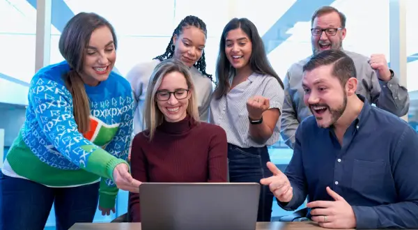 Zespół cieszy się z sukcesu projektu, który jest jak miasto na a. Wszyscy patrzą na ekran laptopa z uśmiechem i entuzjazmem.