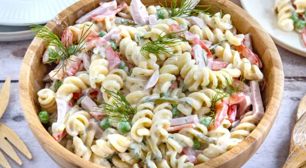 Ein cremiger Nudelsalat mit Schinken, Erbsen und Paprika, garniert mit Dill. Ein leckeres nudelsalat rezept für jede Gelegenheit.