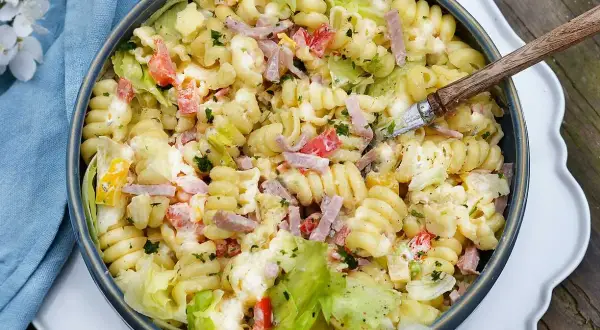 En stor skål med krämig pastasallad med skinka, paprika och sallad. Perfekt dressing till pastasallad för en sommarlunch.