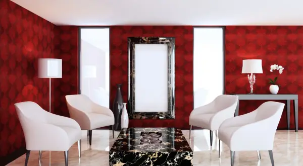 Elegancki salon z tapetą w czerwone obrazy, białymi fotelami i marmurowym stolikiem.