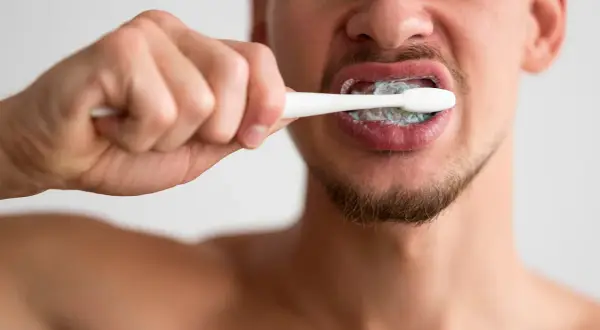 Hombre cepillándose los dientes con pasta. ¿Cuánto tiempo hay que lavarse los dientes? Dos minutos es lo recomendado.