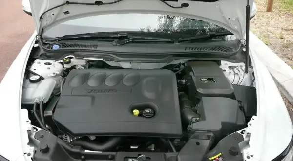 Silnik Volvo V50 2.0D z otwartą maską. Widoczna czarna pokrywa silnika z logo Volvo.