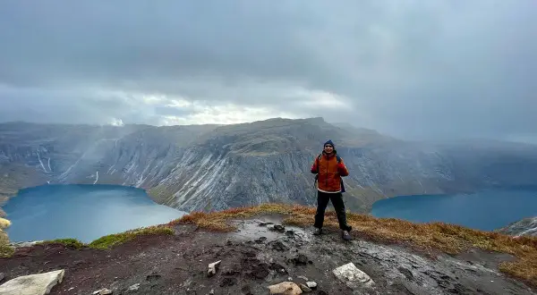 Man på en klippa med en sjö och berg i bakgrunden. En lyckad trolltunga vandring!