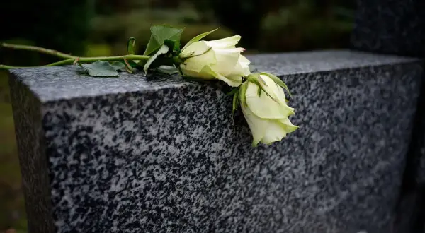 Białe róże na granitowym nagrobku. Czekamy, od kiedy wzrośnie zasiłek pogrzebowy, by godnie pożegnać bliskich.