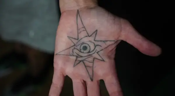 Tatuajes de protección contra el mal y su significado: un ojo dentro de una estrella de ocho puntas en la palma de la mano, símbolo de vigilancia y escudo.
