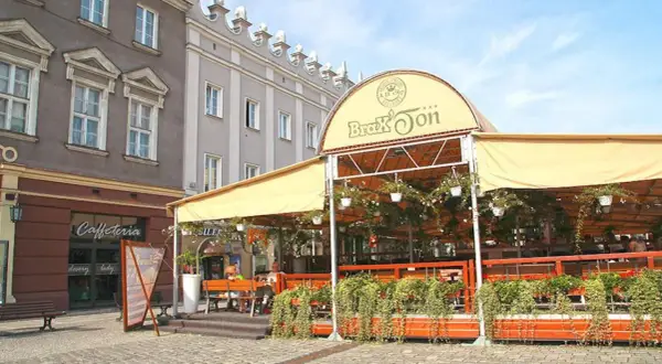 Zadaszony ogródek restauracji Brax'Ton z widoczną kawiarnią w tle.