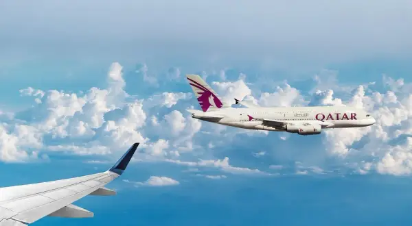 Dwa samoloty pasażerskie lecą nad chmurami. Jeden z nich, z logo Qatar Airways, osiąga średnią prędkość samolotu pasażerskiego.