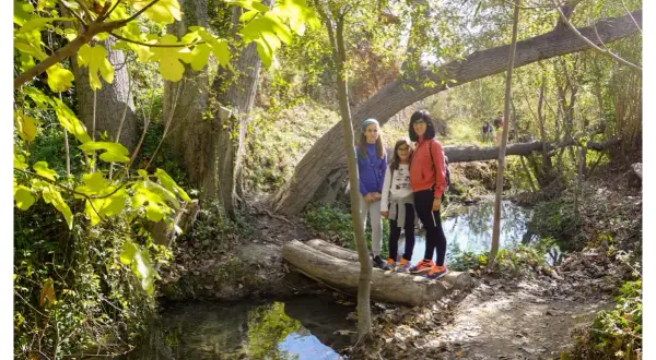 Familia posa en la ruta del agua Sella, disfrutando del sendero boscoso y el arroyo.