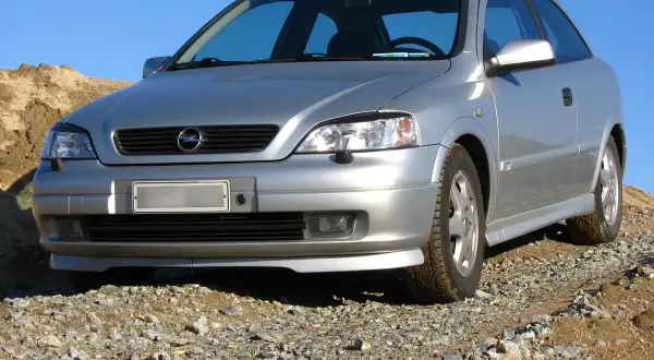 Srebrny Opel Astra G 1.6 16v na kamienistym podjeździe, gotowy na przygodę.
