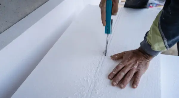Ręce tną styropian, materiał budowlany. Czy styropian jest toksyczny? Pytanie o bezpieczeństwo materiału.