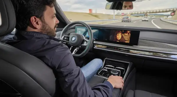 Uomo rilassato in auto, guarda un film mentre il sistema di **traffic jam assist** gestisce la guida in coda.