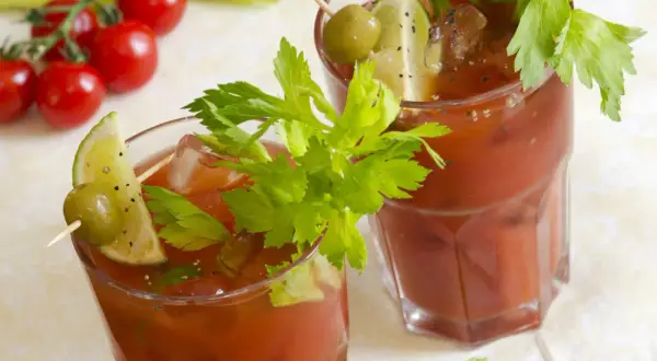 Dwa drinki Krwawa Mary, ozdobione łodygami selera, limonką i oliwką. Historia tego koktajlu jest równie intrygująca, co jego smak.