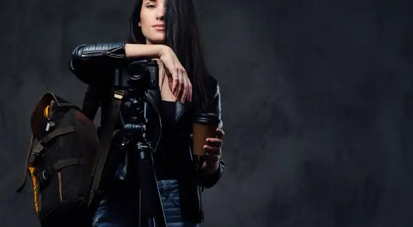 Kobieta z aparatem na statywie i kubkiem kawy, gotowa do uchwycenia niezwykłych kadrów. Opanowała zaawansowane techniki fotograficzne.