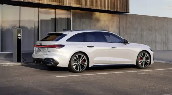Vit Audi A5 hybrid laddas vid en laddstation. Modern design möter hållbarhet.