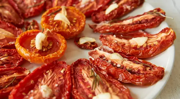 Getrocknete Tomaten mit Knoblauch und Rosmarin auf einem Teller.