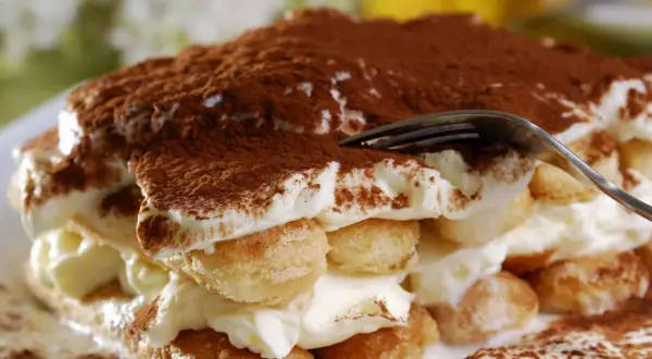 Ein Stück tiramisu originale, mit Löffelbiskuit, Creme und Kakaopulver bestäubt.