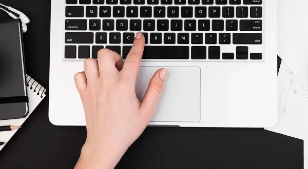 Dłoń naciska klawisz "C" na klawiaturze laptopa, pokazując, jak włączyć klawiaturę.