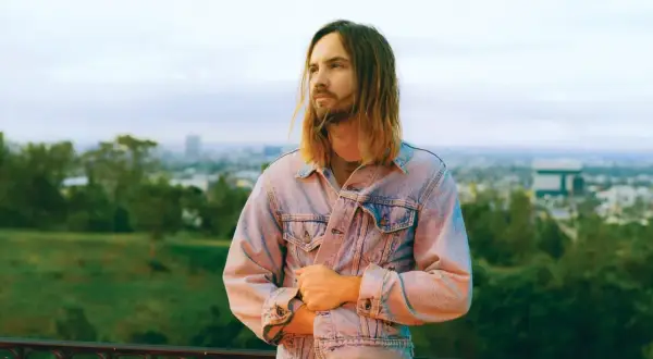 Kevin Parker z Tame Impala Polska w dżinsowej kurtce, z widokiem na miasto.