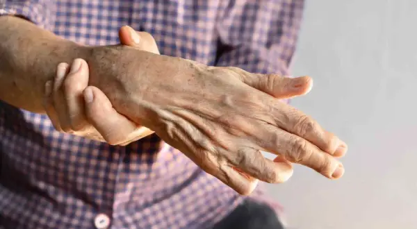 Mano anziana con dita piegate, che ricorda una mano ad artiglio, con la pelle segnata dal tempo.