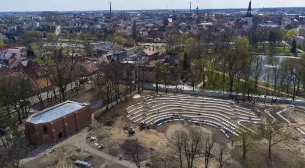 Nowe amfiteatralne trybuny w jarocińskim parku nabierają kształtów. W tle widać panoramę miasta i staw.