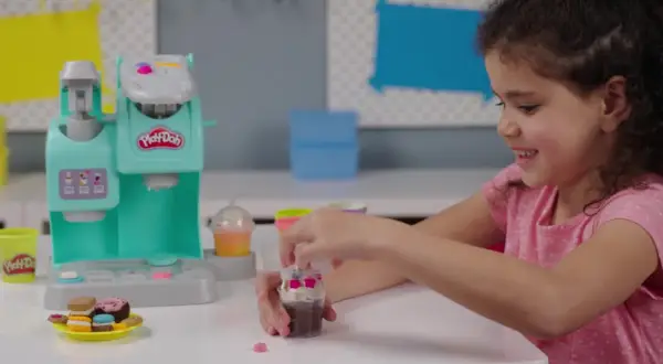Dziewczynka bawi się w play doh kawiarnia, tworząc pyszne desery z plasteliny.