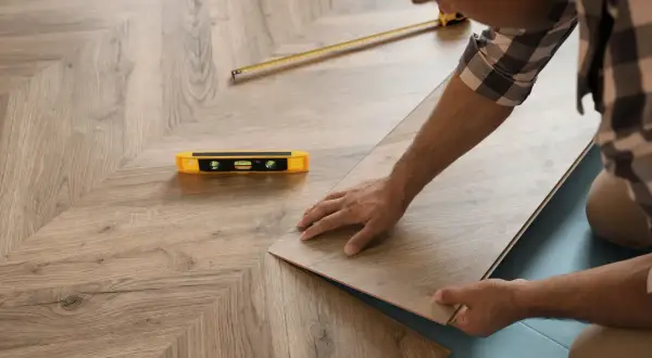 Installazione di un nuovo pavimento in laminato, posato come massetto sopra pavimento esistente. Livella e metro a nastro a portata di mano.