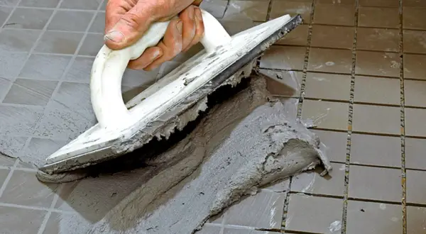 Hand spreading cement with a trowel to foga om kakel.