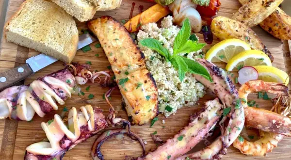 Wyśmienite greckie jedzenie: grillowane kalmary, krewetki, łosoś, pieczone ziemniaki, kasza i pieczywo.