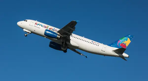 Samolot Smartwings z kolorowym malowaniem globu na ogonie wznosi się na tle błękitnego nieba.