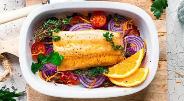 Saftiger Kabeljau im Ofen mit roten Zwiebeln, Tomaten, Kräutern und Orangenscheiben.