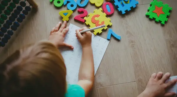 Dziecko ćwiczy pisanie cyfr. Warto wiedzieć, dofinansowanie do żłobka komu przysługuje, by wesprzeć rozwój malucha.