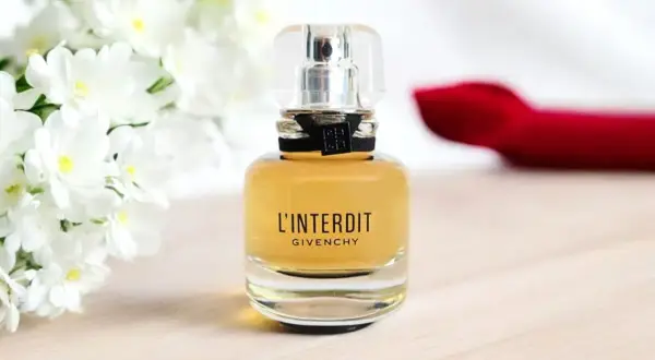 Elegancka butelka Givenchy L'Interdit EDP z białymi kwiatami w tle.