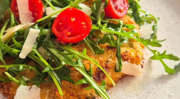 Knuspriges paniertes Hähnchen mit Rucola, Kirschtomaten und Parmesan.