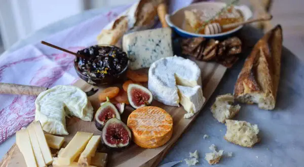 Un plateau gourmand pour explorer l'univers du fromage : brie, bleu, chèvre, pain, figues, abricots secs et miel.